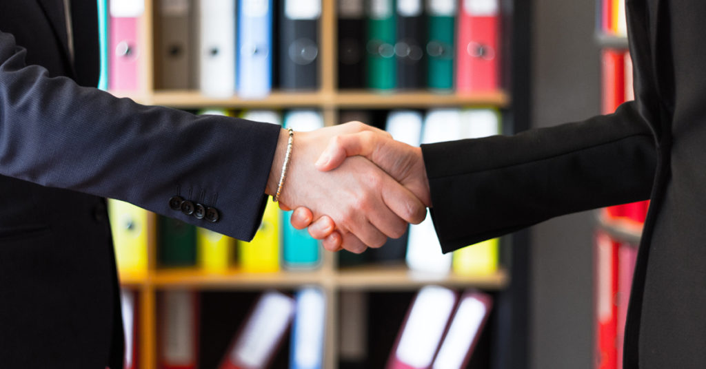 cropped image of a handshake between two people in suit